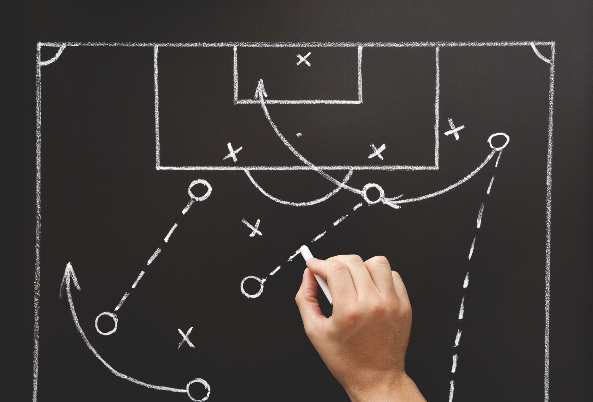 Esquema tático de jogo de futebol desenhado em giz sobre quadro negro.